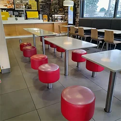 Reupholstered McDonald’s commercial upholstery seating with vibrant red stools and modern grey benches, refreshed for durability and a clean, welcoming dining space.
