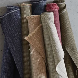 Selection of durable upholstery fabric rolls in earthy shades of navy, beige, olive, and red, ideal for giving furniture a refreshed, long-lasting finish.